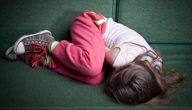 niña acostada en sillon llorando